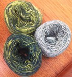 Perle 8 balls of white cotton painted with mixtures of navy and yellow.  The one on the right is  a heavy dilution of the dye in the bath